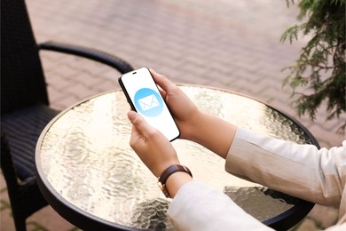 New message notification. Woman with mobile phone at outdoor cafe, closeup