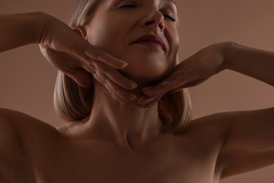 Photo of Beautiful woman touching her neck on beige background, closeup