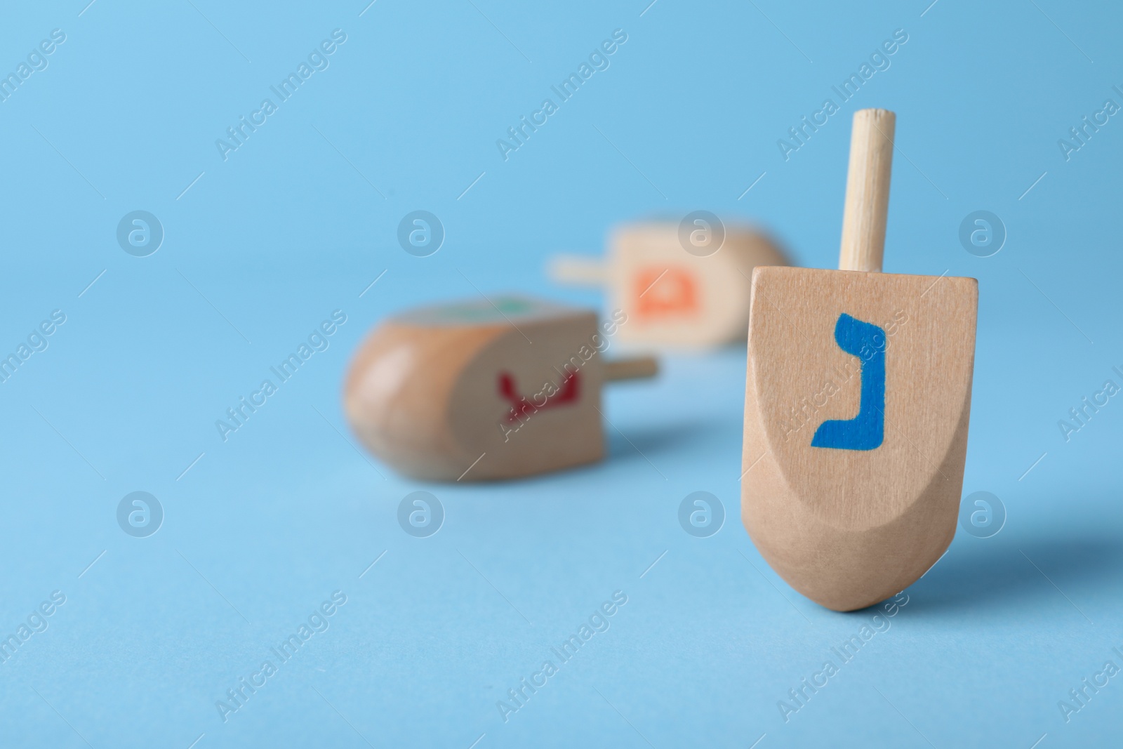 Photo of Hanukkah traditional dreidel with letter Nun on light blue background, space for text