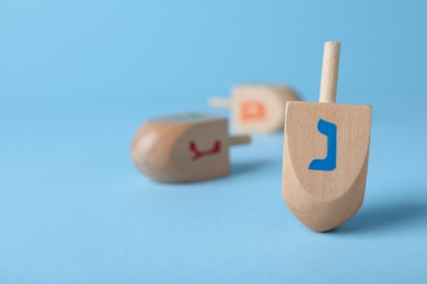Photo of Hanukkah traditional dreidel with letter Nun on light blue background, space for text