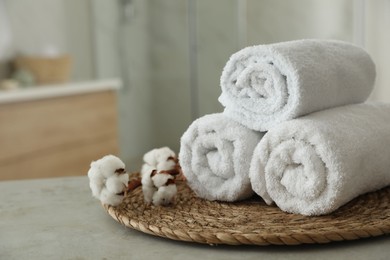 Photo of Clean rolled towels and cotton flowers on table in bathroom. Space for text