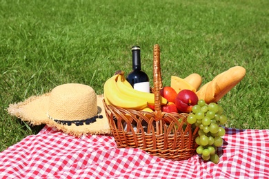 Basket with food on blanket prepared for picnic in park