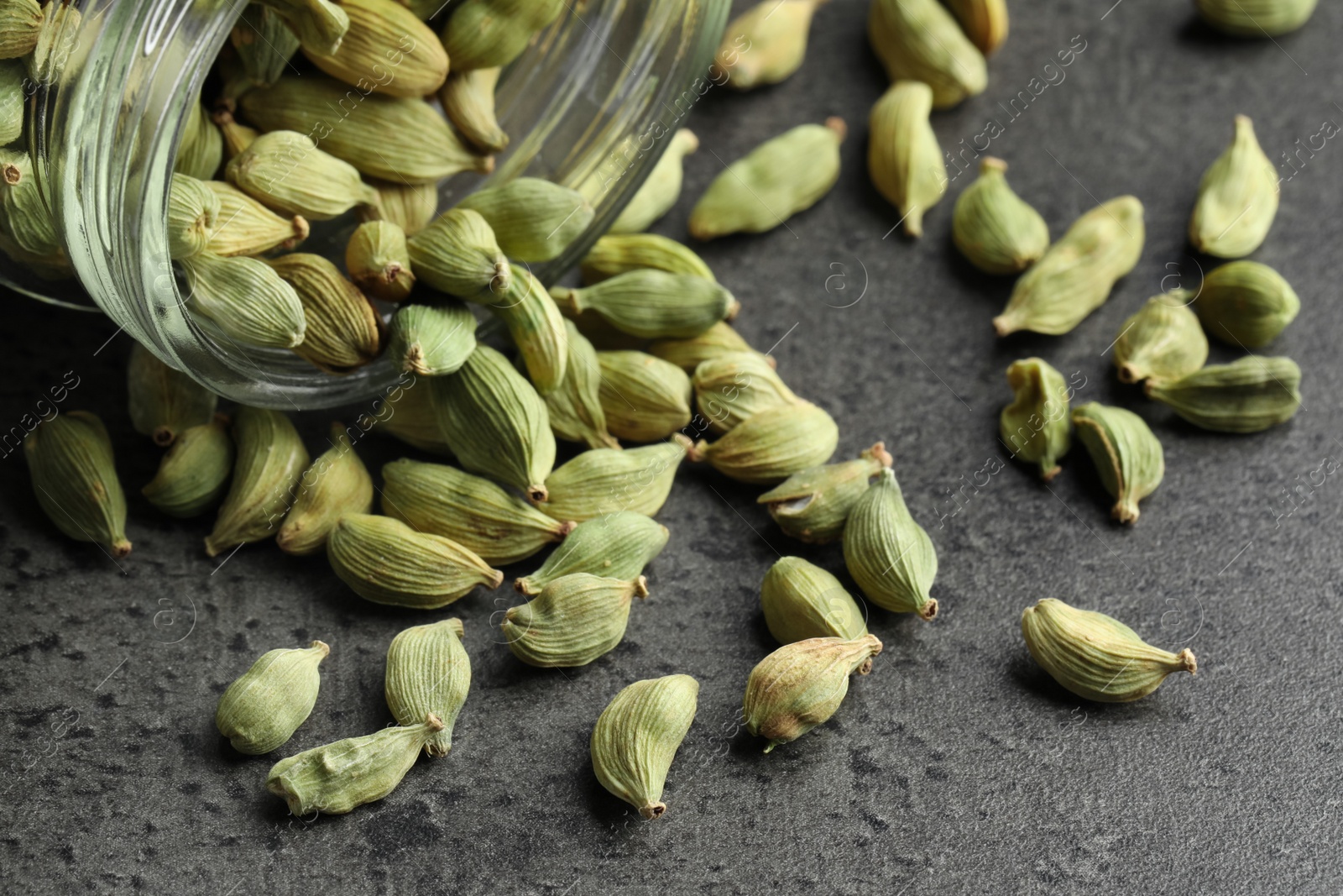 Photo of Jar with dry cardamom pods on dark grey table