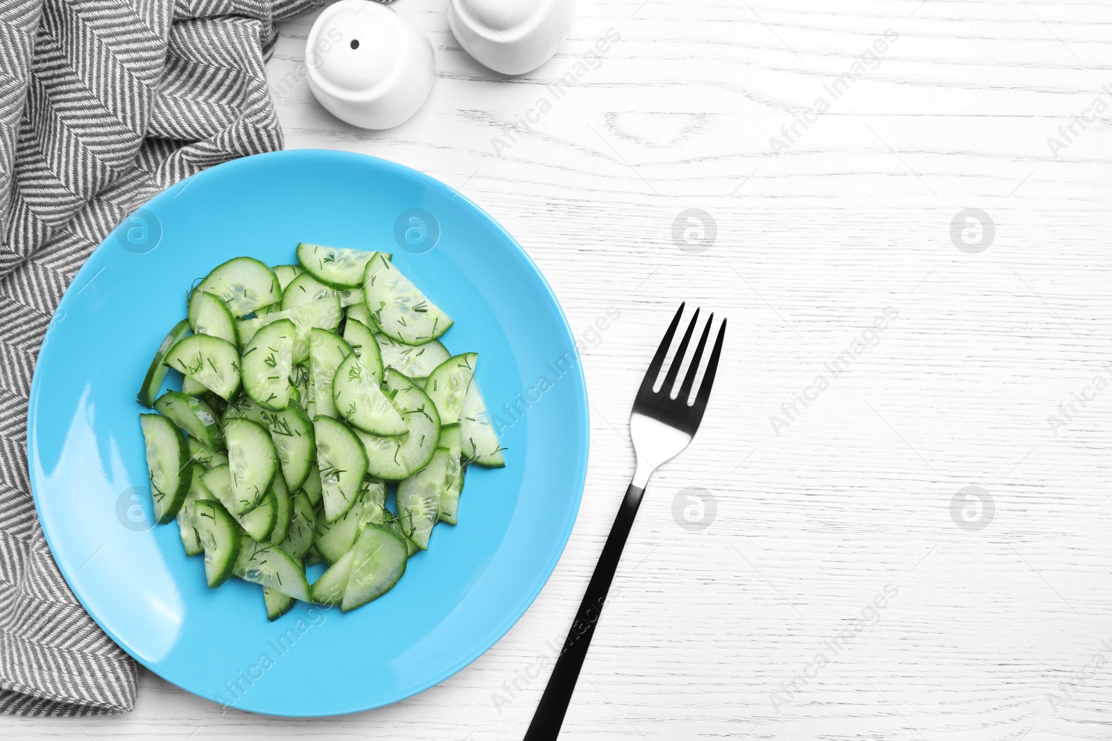 Photo of Plate of tasty cucumber salad served on white wooden table, flat lay. Space for text