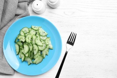 Plate of tasty cucumber salad served on white wooden table, flat lay. Space for text