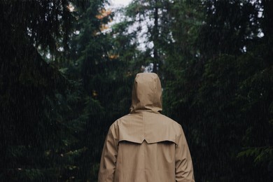 Photo of Woman with raincoat in forest under rain, back view
