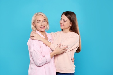 Portrait of mature woman and her daughter on color background