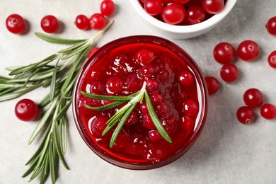 Photo of Cranberry sauce, rosemary and fresh berries on light table, flat lay