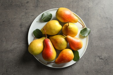 Plate with ripe pears on grey background, top view