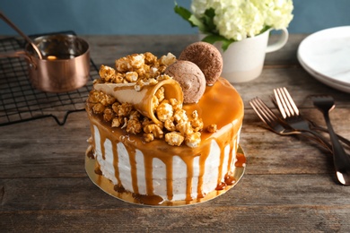 Delicious homemade cake with caramel sauce and popcorn on table