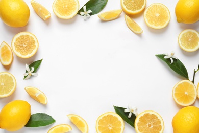 Frame made of lemons, leaves and flowers on white background, top view with space for text. Citrus fruits