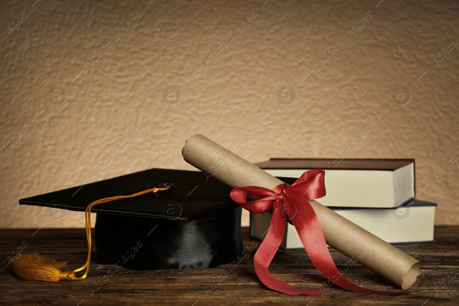 Image of Graduation hat, books and diploma on wooden table