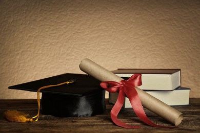 Image of Graduation hat, books and diploma on wooden table