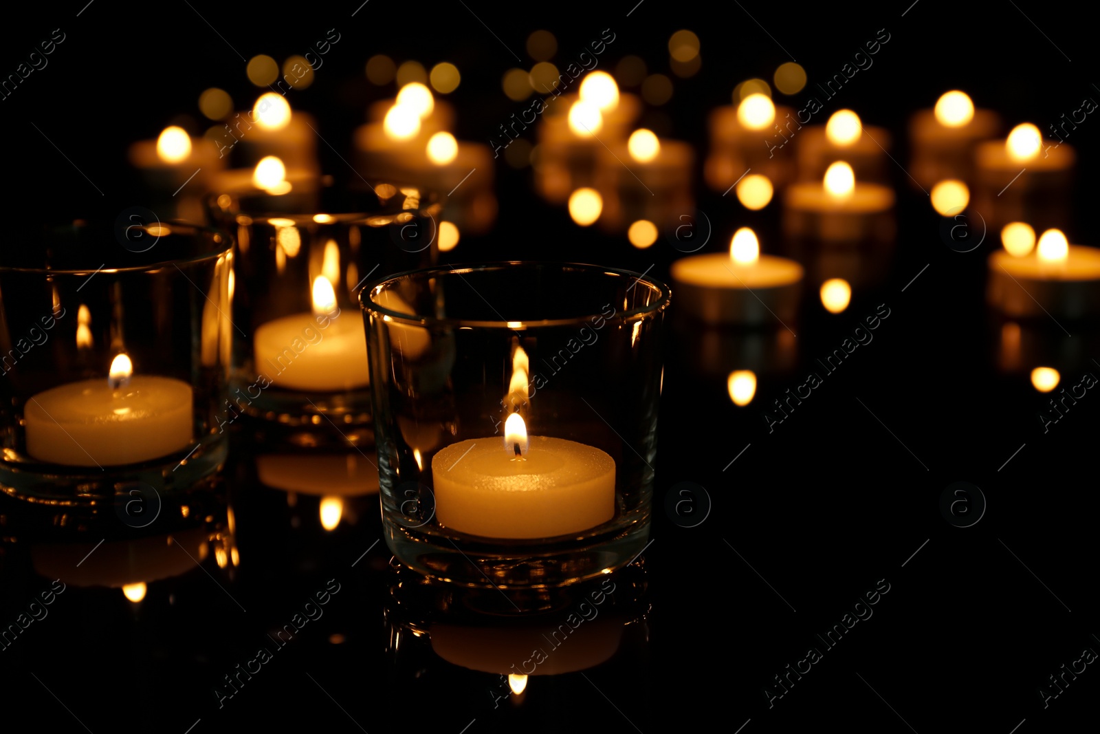 Photo of Burning candles in glass holders on table