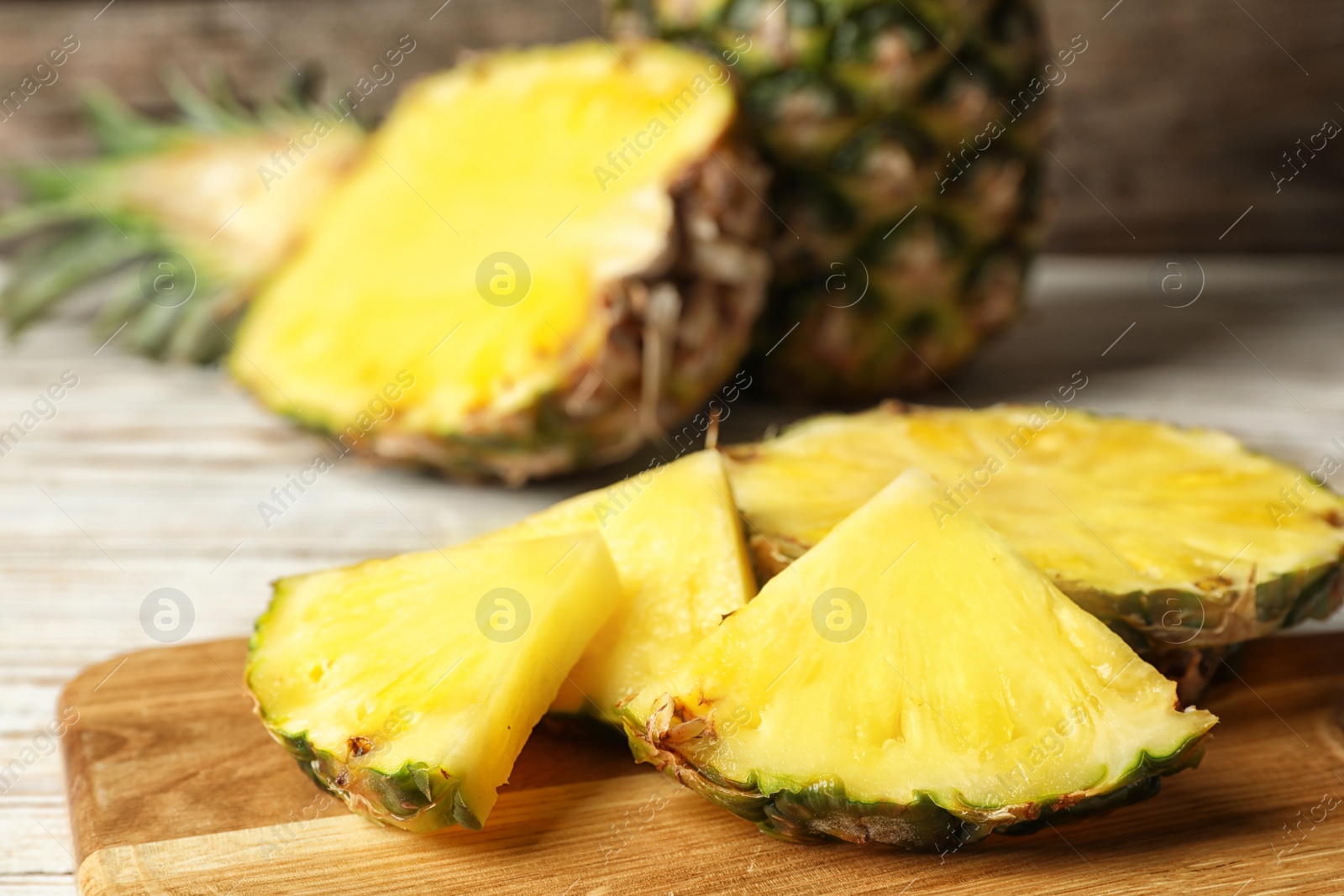 Photo of Cut fresh juicy pineapple on wooden board, closeup