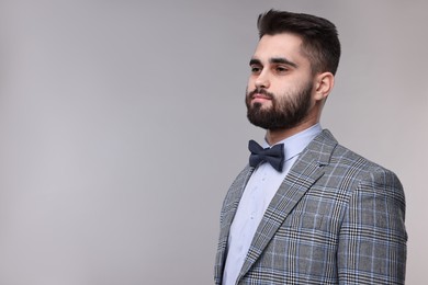 Photo of Portrait of handsome man in suit, shirt and bow tie on grey background. Space for text