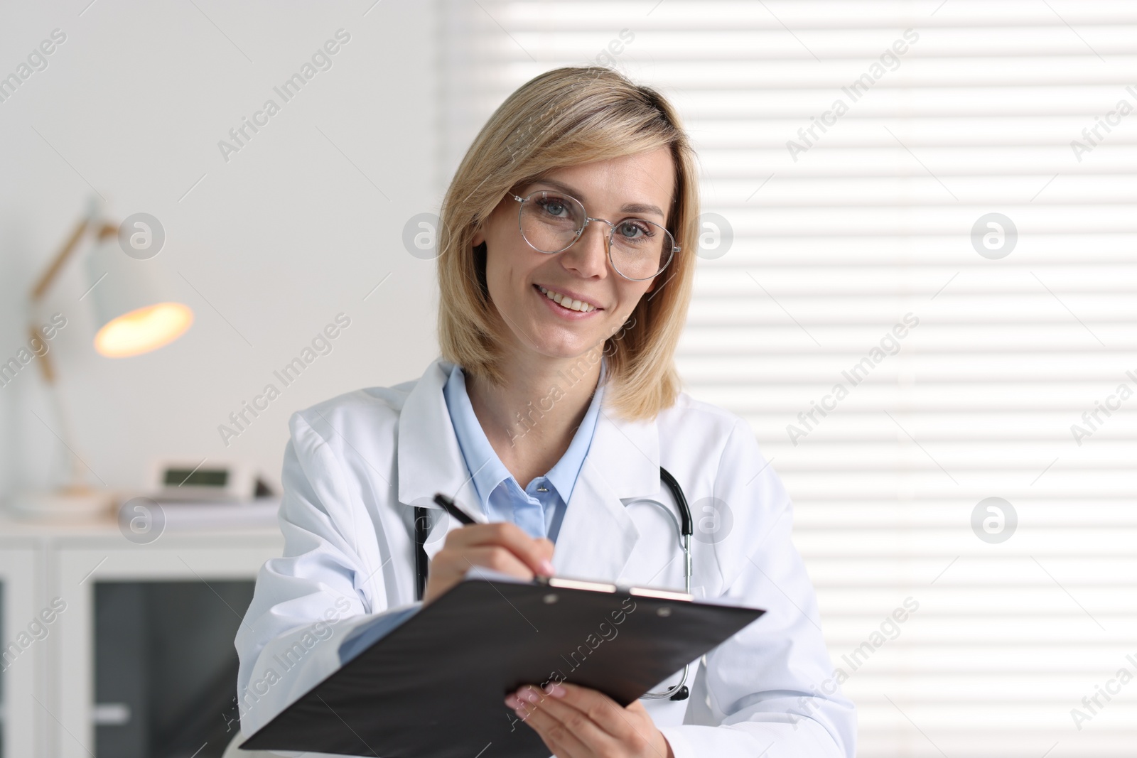 Photo of Portrait of smiling doctor with clipboard in office
