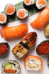 Different tasty sushi rolls on white background, flat lay