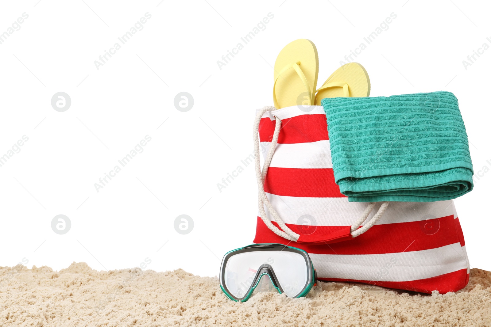 Photo of Stylish bag with beach accessories on sand against white background