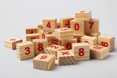 Wooden cubes with numbers and mathematical symbols on light background