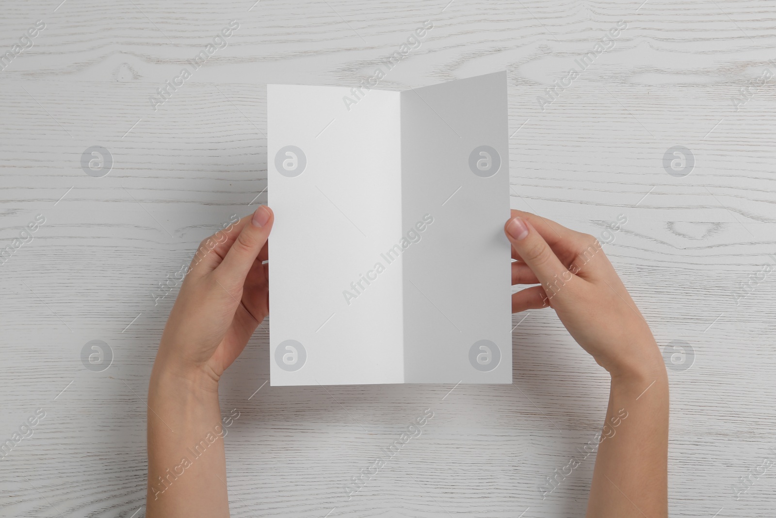 Photo of Woman with blank brochure on wooden background, above view. Mock up for design