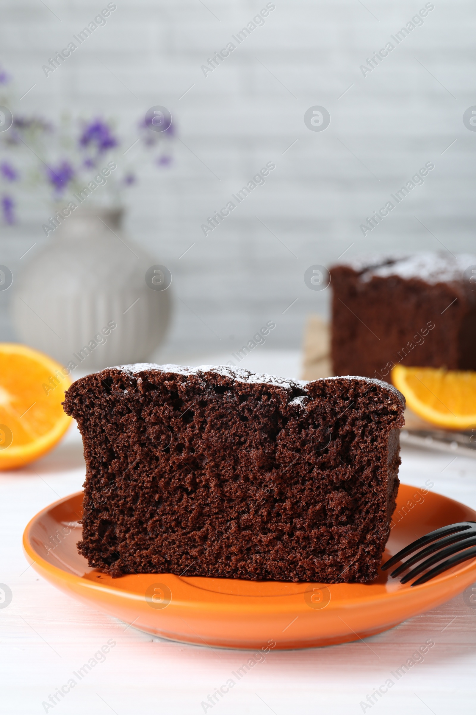 Photo of Piece of tasty chocolate sponge cake with powdered sugar on white table