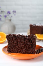 Piece of tasty chocolate sponge cake with powdered sugar on white table