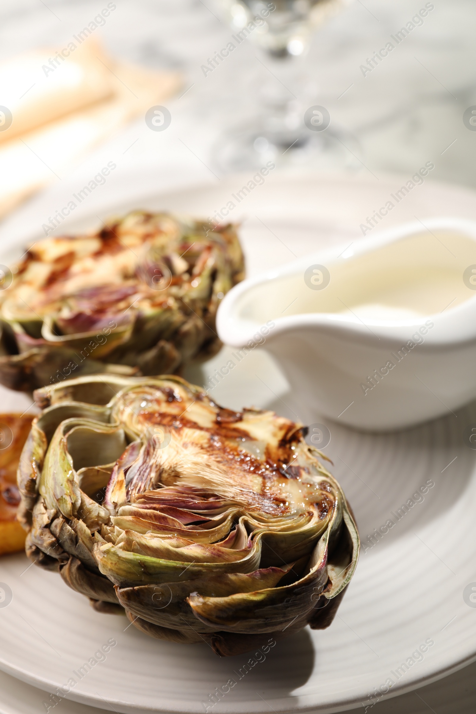 Photo of Tasty grilled artichokes on plate, closeup view