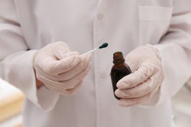 Doctor holding bottle of brilliant green and cotton bud, closeup