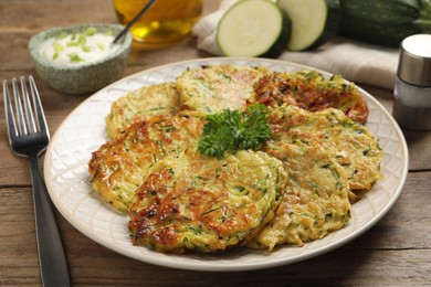 Photo of Delicious zucchini fritters served on wooden table