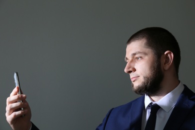 Man unlocking smartphone with facial scanner on grey background. Biometric verification