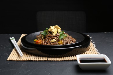 Photo of Stir-fry. Tasty noodles with meat and vegetables served on dark textured table