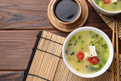 Photo of Bowl of delicious miso soup with tofu served on wooden table, flat lay. Space for text