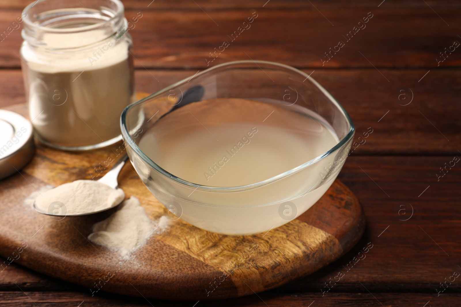 Photo of Glass bowl of agar-agar jelly and powder on wooden table