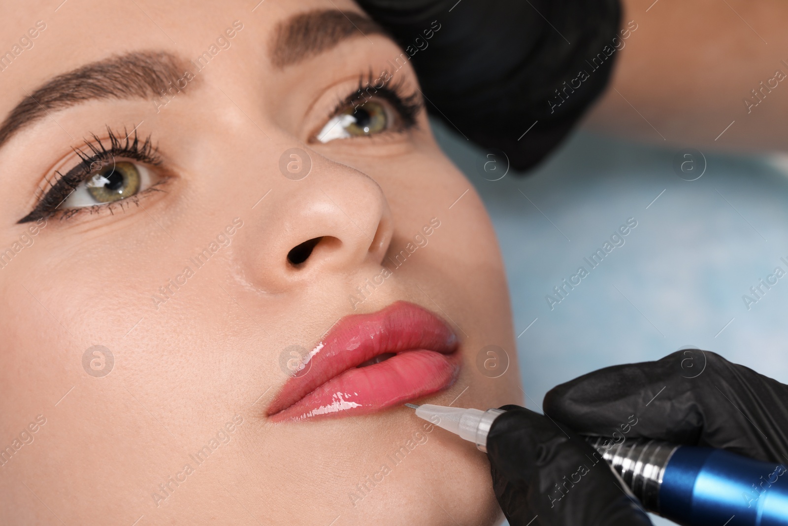 Photo of Young woman during procedure of permanent lip makeup in beauty salon, closeup