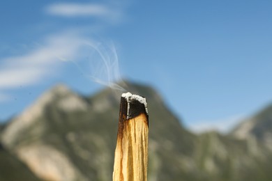 Photo of Burning palo santo stick in high mountains, closeup