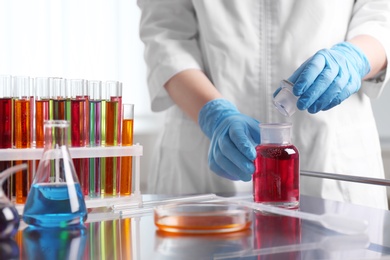 Scientist working at table with glassware in laboratory, closeup. Solution chemistry