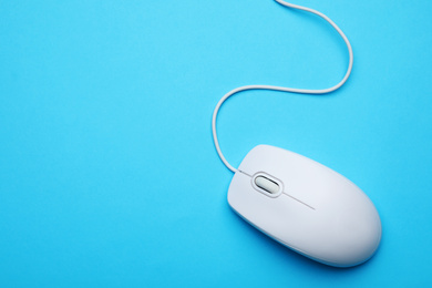 Wired computer mouse on light blue background, top view. Space for text