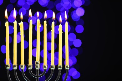 Hanukkah celebration. Menorah with burning candles against dark background with blurred lights, space for text
