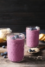 Photo of Jars with blueberry smoothies on wooden table