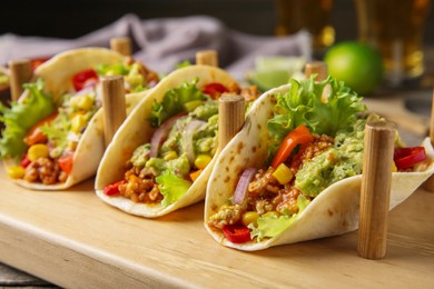Delicious tacos with guacamole, meat and vegetables served on table, closeup