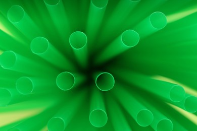 Photo of Heap of green plastic straws for drinks, closeup