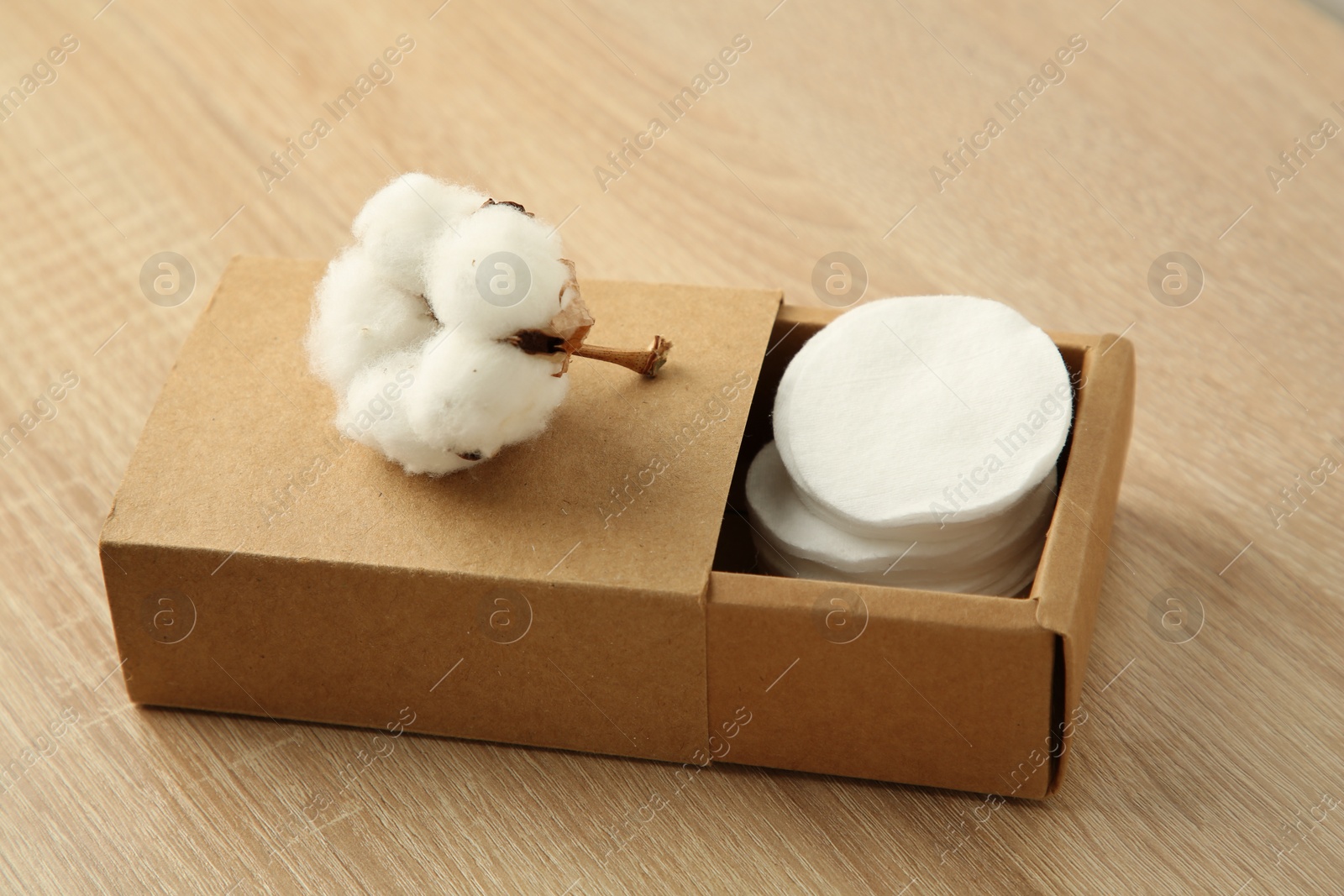 Photo of Cotton pads and flower on wooden table, closeup