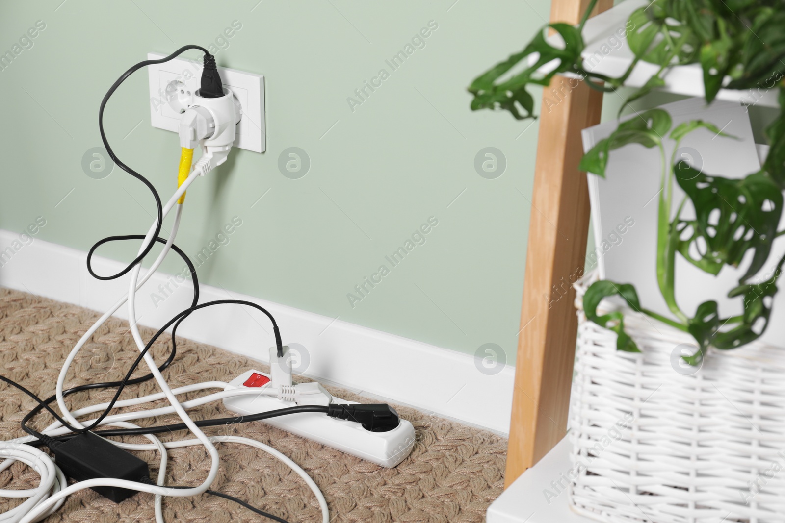 Photo of Different electrical plugs in socket and power strip on floor indoors