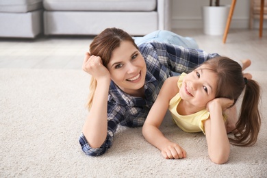Photo of Cute little girl and her mother lying on cozy carpet at home