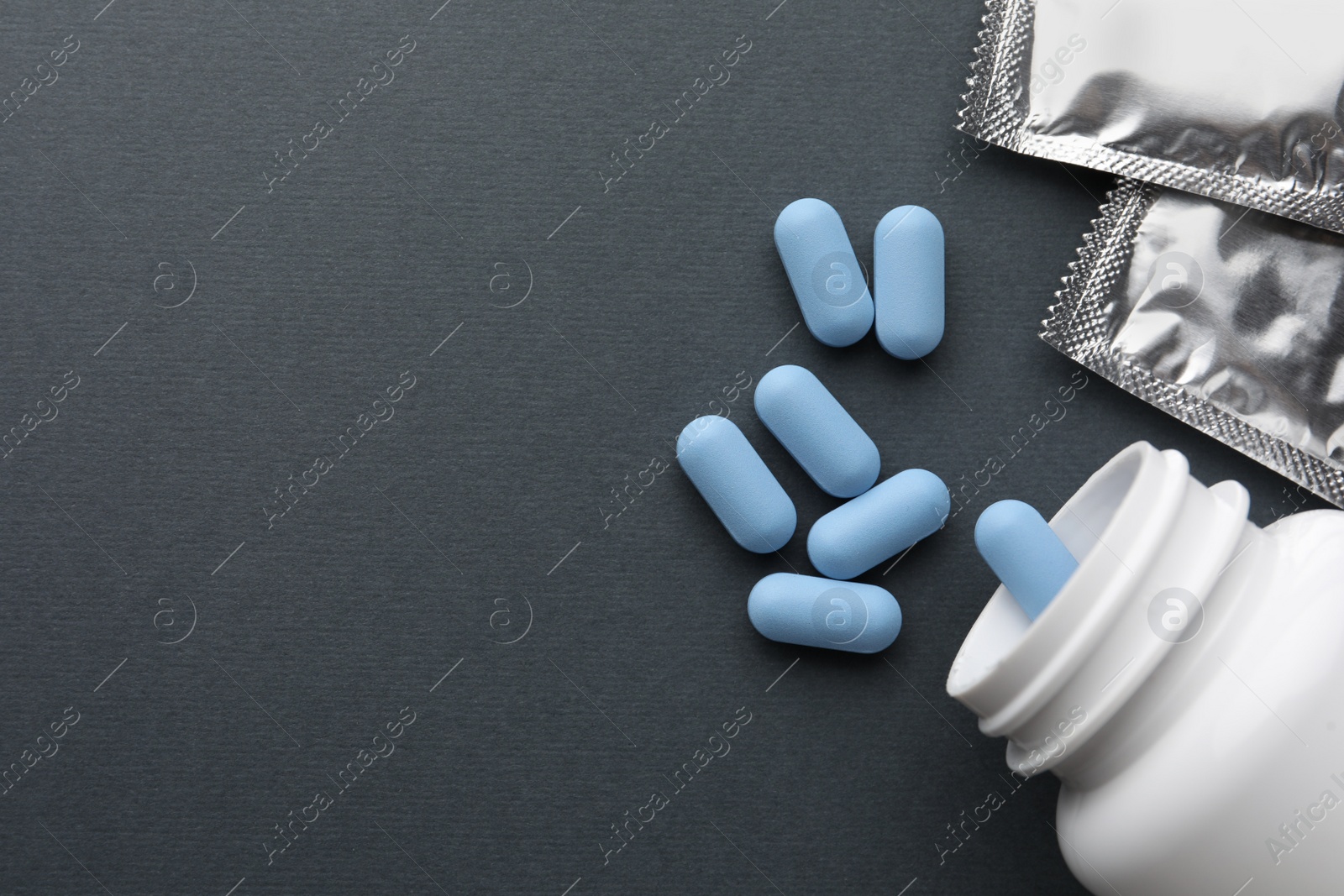 Photo of Pills and medical bottle on dark gray background, flat lay with space for text. Potency problem