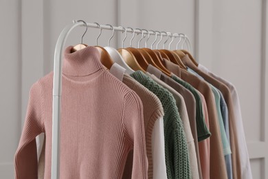 Photo of Rack with stylish clothes near light wall