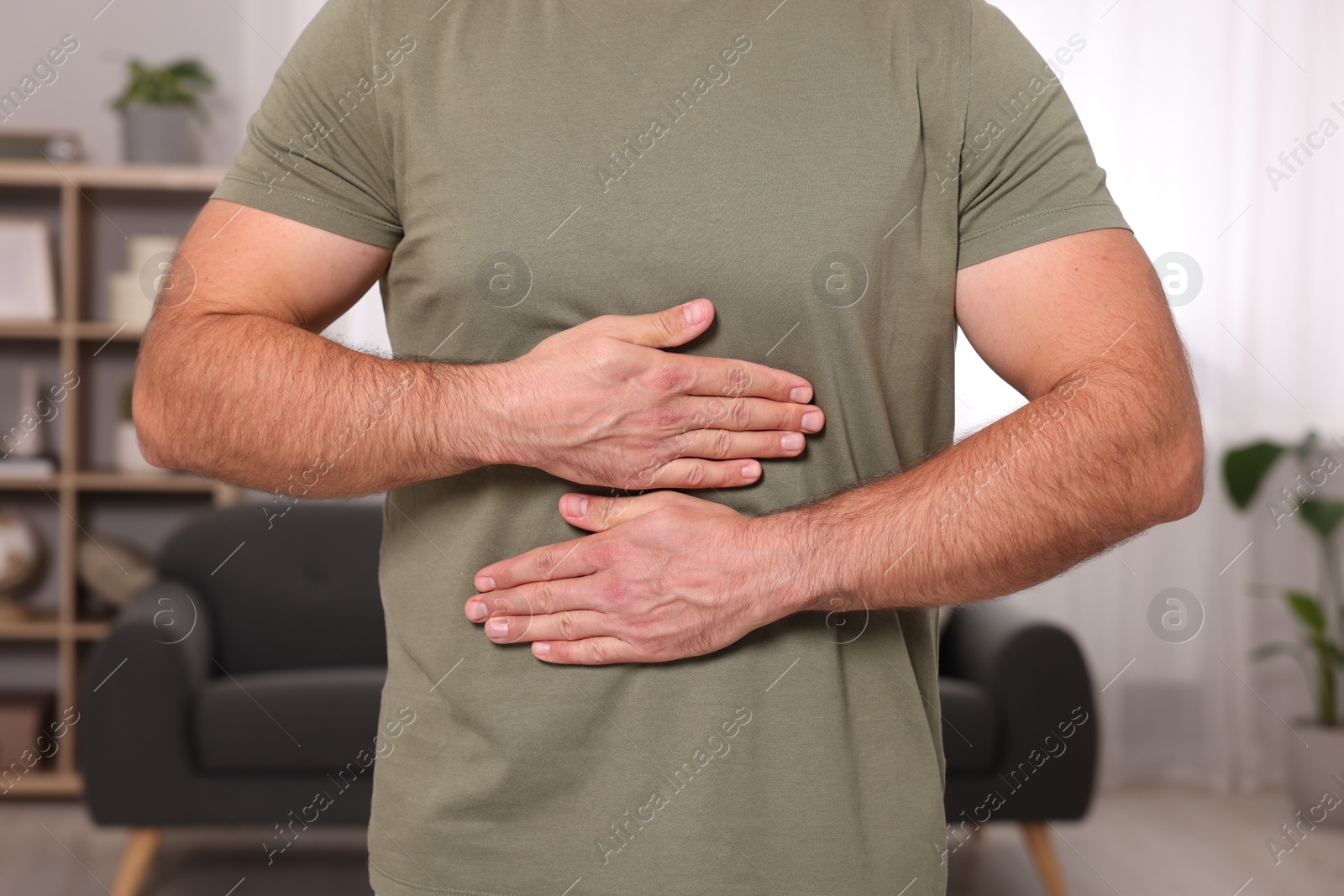 Photo of Man suffering from stomach pain at home, closeup