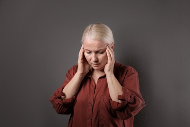 Mature woman suffering from depression on grey background