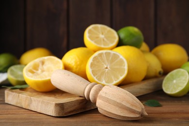 Squeezer with lemons on wooden table, closeup